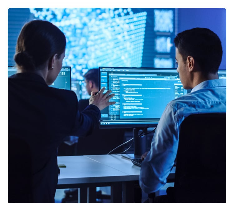 A woman points to a computer screen in a SOC